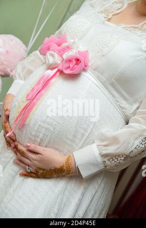 Schwangere Frau im Kleid hält die Hände auf dem Bauch. Schwangerschaft, Mutterschaft, Vorbereitung und Erwartung Konzept. Nahaufnahme, Kopierbereich, Innenbereich. Schöne zehn Stockfoto