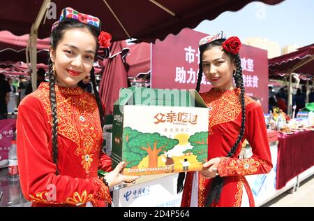 (201010) -- URUMQI, 10. Oktober 2020 (Xinhua) -- Mädchen zeigen lokale Spezialitäten während einer Live-Streaming-Aktivität in einem Jade-Handelszentrum in Hotan, im Nordwesten Chinas Xinjiang Uygur Autonome Region, 27. Mai 2020. Dank der Anstrengungen von allen Seiten sind in Xinjiang große Fortschritte erzielt worden. Von 2014 bis 2019 wurde eine solide wirtschaftliche Dynamik mit einer durchschnittlichen jährlichen BIP-Wachstumsrate von 7.2 Prozent aufrechterhalten. Der Lebensstandard der lokalen Bevölkerung hat sich mit einem durchschnittlichen jährlichen Wachstum von 9.1 Prozent des verfügbaren Pro-Kopf-Wohneinkommens und mehr als 2.92 Millionen deutlich verbessert Stockfoto