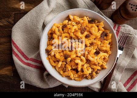 Schüssel mit Makkaroni und Käse mit Speckstücken auf einem rustikalen Holztisch. Overhead-Ansicht Stockfoto