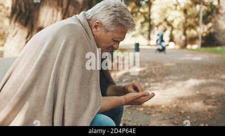 Der arme ältere Obdachlose, der zählte, hinterließ am Herbsttag Münzen im Park. Hochwertige Fotos Stockfoto