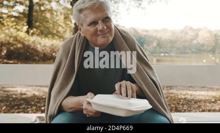 Obdachloser Mann mit einem Lächeln, der Essen von einem Freiwilligen erhält. Hochwertige Fotos Stockfoto