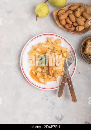 Dünne Palatschinken (Pfannkuchen) mit Apple füllen, gefüllte Brötchen, Russische traditionelle Lebensmittel für die maslenitsa, französischer Nachtisch, Frühstück mit Tulpen auf Mutter d Stockfoto