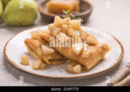 Dünne Palatschinken (Pfannkuchen) mit Apple füllen, gefüllte Brötchen, Russische traditionelle Lebensmittel für die maslenitsa, französischer Nachtisch, Frühstück mit Tulpen auf Mutter d Stockfoto