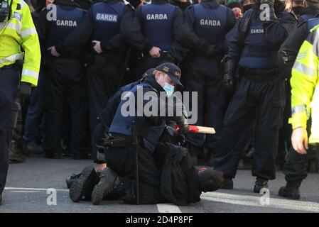 Mitglieder eines Garda entfernen während eines Anti-Lockdown-Protests vor dem Leinster House, Dublin, einen Gegendemonstrator, da Irland weiterhin landesweit an einer Stufe 3-Coronavirus-Sperre erkranst. Stockfoto