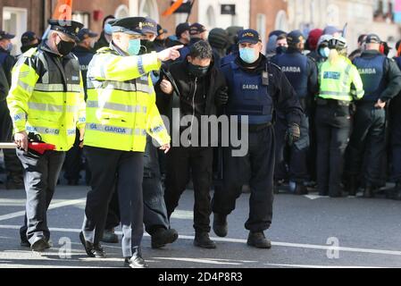 Mitglieder eines Garda entfernen während eines Anti-Lockdown-Protests vor dem Leinster House, Dublin, einen Gegendemonstrator, da Irland weiterhin landesweit an einer Stufe 3-Coronavirus-Sperre erkranst. Stockfoto