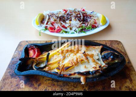 Forelle in Tonerde Topf. Gebacken im Ofen mit Cheddar, Kartoffeln und Gemüse. Präsentation mit gemischten Gemüsesalat Stockfoto
