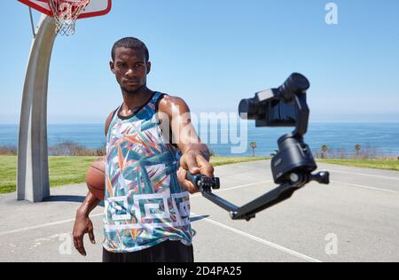 Junger afroamerikanischer Sportler mit Basketballball und Selfie Stick Stockfoto
