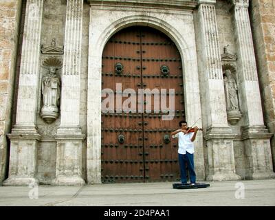 MERIDA, MEXIKO - 06. Jan 2010: Merida, Yucatan / Mexiko - 5. Januar 2010: Der Geiger Mann spielt vor der massiven Holztür einer Weißen Kathedrale Stockfoto