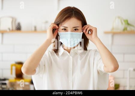 Schöne junge asiatische Frau setzen auf eine Maske auf Gesicht Stockfoto