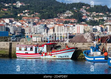 PORTONOVO, SPANIEN - 15. AUGUST 2020: Bunte kleine Fischerboote, die in Portonovo Hafen in der Abenddämmerung, Galizien, Spanien, festgemacht sind. Stockfoto