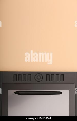 Grafikmonitor Stift auf peachy Farbtabelle. Schwarzer Tablet-Computer mit leerem Bildschirm. Hochauflösendes Foto. Volle Schärfentiefe. Arbeitsumgebung Stockfoto