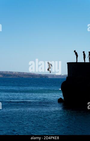 Gruppe von Freunden springen in mittelmeer von Felsen Klippe Stockfoto