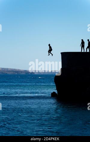 Gruppe von Freunden springen in mittelmeer von Felsen Klippe Stockfoto