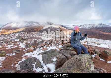 Walker auf dem Gipfel des munro-Berges von Carn O Mhaim in Glen Lui bei Braemar, Aberdeenshire, Schottland, Großbritannien. Ben Macdui ist im Hintergrund Stockfoto