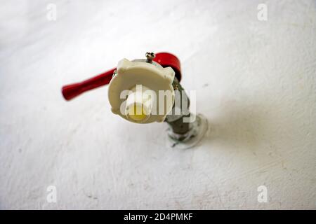 Der Wasserhahn in einer Wand, Blick von unten. Der Wasserhahn mit Schlauchanschluss. Stockfoto