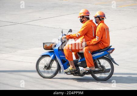 SAMUT PRAKAN, THAILAND, 29 2020. JULI, zwei Männer in den orangen Overalls fahren ein Motorrad. Stockfoto