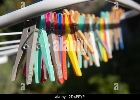 Eine farbige Kleidung hängt an einem Trockengestell Draht. Eine Gruppe von Wäscheklammern in der Schlange am Stand im sonnigen Garten. Stockfoto