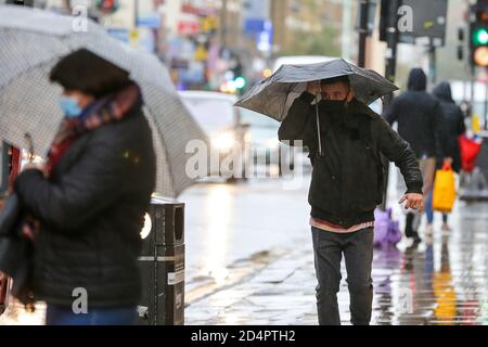 London, Großbritannien. Oktober 2020. An einem regnerischen Tag laufen die Menschen durch die Straßen, während sie Regenschirme halten. Kredit: SOPA Images Limited/Alamy Live Nachrichten Stockfoto