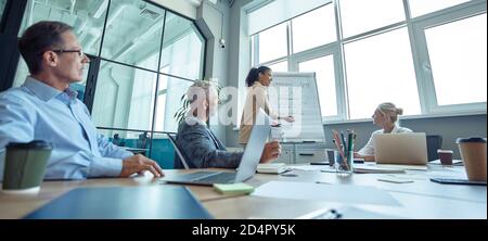 Junge Mixed Race Frau etwas auf Flipchart schreiben, eine Präsentation geben und diskutieren Geschäftsstrategie mit Kollegen, Startup-Team arbeiten Stockfoto