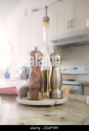 Auf der Küchentheke gibt es Salz, Pfeffer, Zimt und Olivenöl. Eine Salzmühle aus Edelstahl und eine Pfeffermühle aus Holz. Stockfoto