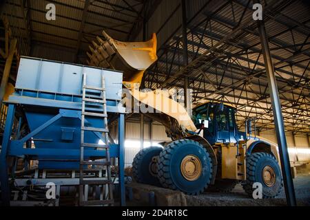 Region Aktobi/Kasachstan - Mai 04 2019: Phosphatdüngeanlage. Caterpillar Planierraupe oder Bagger Laden von Rohstoffen (Mineralien) in Maschine h Stockfoto