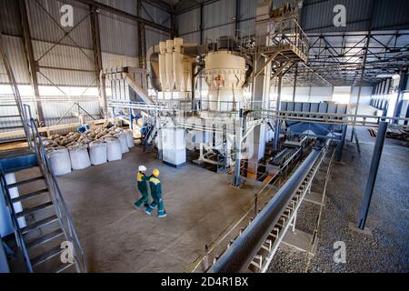 Region Aktobi/Kasachstan - Mai 04 2019: Phosphatdüngeanlage. Maschine für Granulat (Pellets) Produktion. Fabrikwerkstatt und zwei Arbeiter. Stockfoto