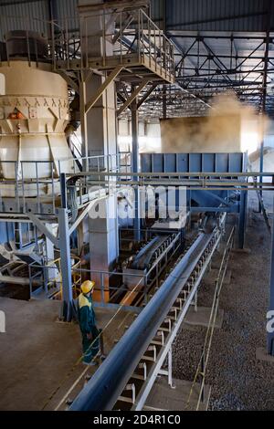 Region Aktobi/Kasachstan - Mai 04 2019: Phosphatdüngeanlage. Maschine für Pellets Produktion. Bediener in gelben Helm steuert Prozess. Stockfoto