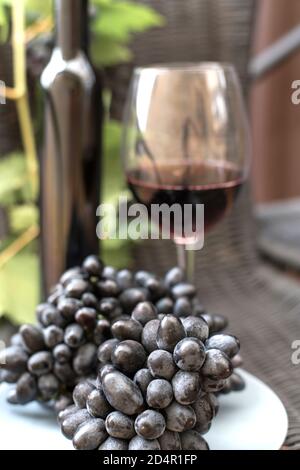 Glas und Flasche dunklem Rotwein und Weintrauben auf Ein dunkler Hintergrund Stockfoto