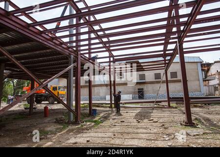 Schymkent, Kasachstan. Bau des Industriegebäudes der chemischen pharmazeutischen Fabrik Santo. Schweißer und Schweißgasschläuche. Stockfoto