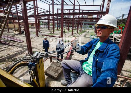 Schymkent/Kasachstan - April 27 2012: Bau eines neuen Industriegebäudes. Kranführer bei der Arbeit. Stockfoto