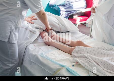 Quadriplegic Patient hospitalisiert in einem PMR-Raum (Person mit eingeschränkter Mobilität), unterstützt von einer Krankenschwester und einem Betreuer. Pflege, Prävention und Überwachung Stockfoto