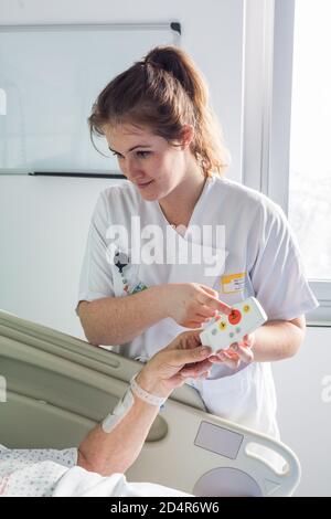 Mann im Krankenhauszimmer, Krankenschwester ruft Fernbedienung, Bordeaux Krankenhaus, Frankreich. Stockfoto
