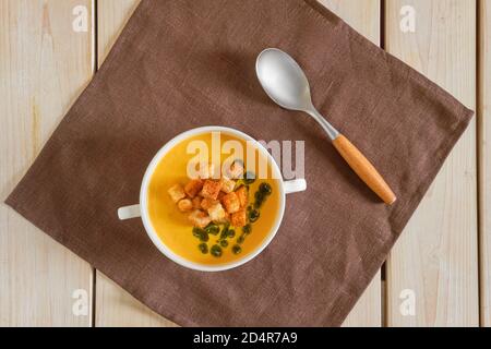 Draufsicht auf gestrichene Erbsensuppe mit Curry und Crouton auf Holztisch Stockfoto