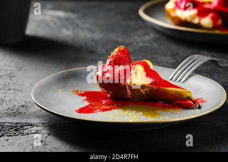 Nahaufnahme von süß gebackenen Birnen mit Mascarpone, Karamellsirup und Erdbeermarmelade Stockfoto