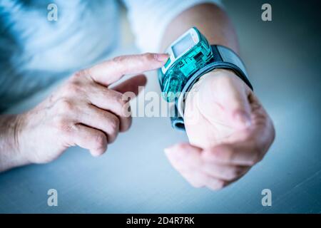 Frau, die ihren Blutdruck mit ein tragbares Blutdruckmessgerät. Stockfoto