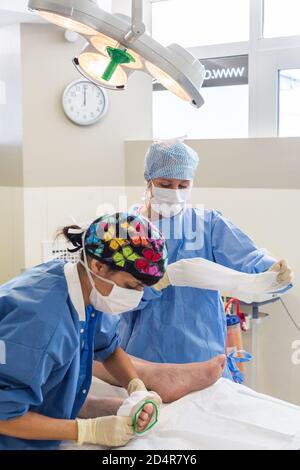 Krankenschwester, die nach der Operation ein System zur Prävention von tiefen Venenthrombosen (DVT) an die Unterschenkel eines Patienten anpasst, ästhetisches Privatkrankenhaus von Aquitaine, Bo Stockfoto