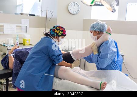 Krankenschwester, die nach der Operation ein System zur Prävention von tiefen Venenthrombosen (DVT) an die Unterschenkel eines Patienten anpasst, ästhetisches Privatkrankenhaus von Aquitaine, Bo Stockfoto