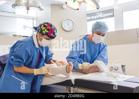 Krankenschwester, die nach der Operation ein System zur Prävention von tiefen Venenthrombosen (DVT) an die Unterschenkel eines Patienten anpasst, ästhetisches Privatkrankenhaus von Aquitaine, Bo Stockfoto