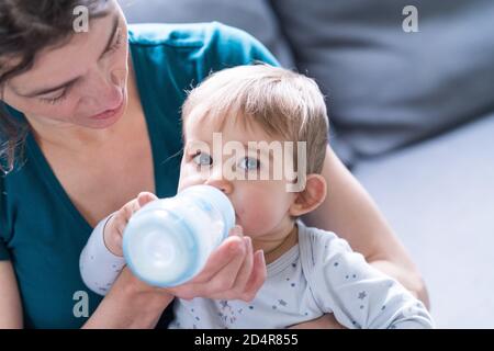 9 Monate Baby Mädchen trinken Milch aus einer Flasche. Stockfoto