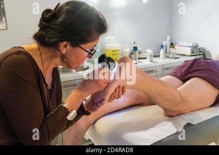 Hautarzt untersucht die Haut eines Patienten mit einem Dermatoskop. Stockfoto