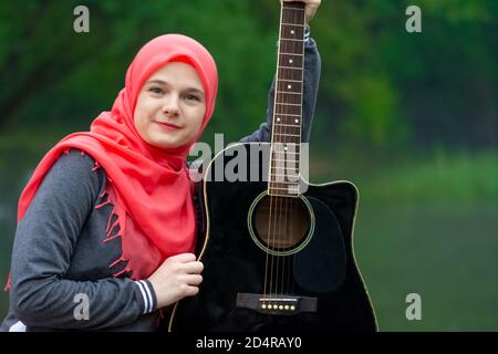 Portrait von blauäugigen muslimischen Mädchen mit Gitarre Stockfoto