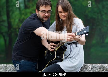 Bruder lehrt Schwester Gitarre in der Natur zu spielen Stockfoto