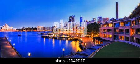 Blue Hour Panorama in Sydney Stadt rund um Circular Quay Waterfront am Hafen von Sydney mit Lichtern, die sich im Wasser spiegeln. Stockfoto