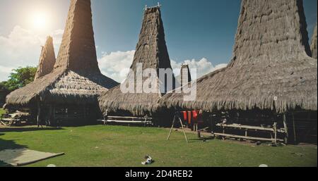 Sonne über traditionellen Haus Dorf auf Grün Tal Luftbild. Indonesische Siedlung mit Strohdachhäusern an grünen tropischen Bäumen. Sommerurlaub im einzigartigen Indonesien Wahrzeichen bei weichem Sonnenlicht Stockfoto