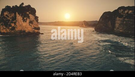 Sonnenuntergang am Felsküste mit Wellen am Meer. Wasseroberfläche in niemand Naturlandschaft bei Sonnenuntergang über dem Meer ruhige Uferpromenade. Sommerlandschaft mit Felsküste bei sanftem Sonnenlicht. Filmaufnahme Stockfoto