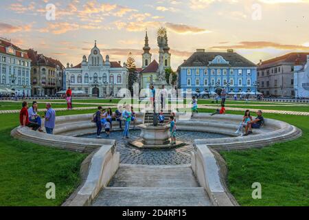 Timisoara, Romani - 2. August 2016 Sonnenuntergangsszene auf dem Unirii-Platz (Union Square), Timisoara, Rumänien mit Fokus auf den zentralen Brunnen mit Menschen genießen Stockfoto