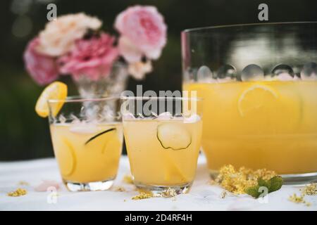 Zitronenschale mit zwei Gläsern und Blumen Stockfoto