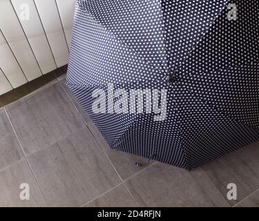 Ein grauer Regenschirm mit Punkten in der Halle auf dem Grauer Fußboden Stockfoto