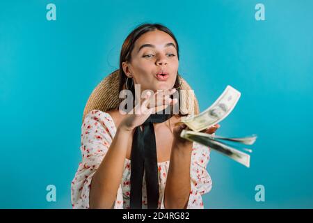 Hübsche Frau mit glücklichen Gesicht streut, Geld verschwenden. Mädchen überausgeben US-Währung. Lady ist bündig mit Dollar auf blauem Studio-Hintergrund. Stockfoto