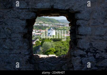 Windmühle durch eine Lücke von Obidos Mauern gesehen, Portugal Stockfoto